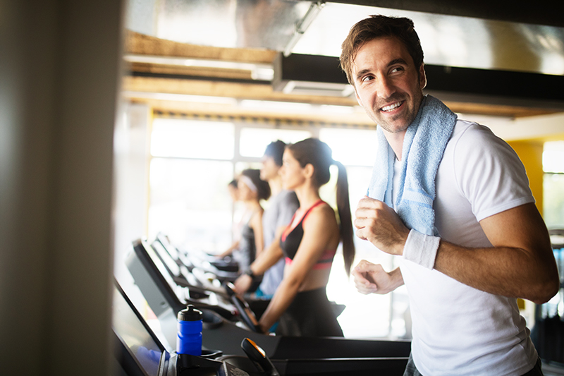 man working out on treadmill smiling