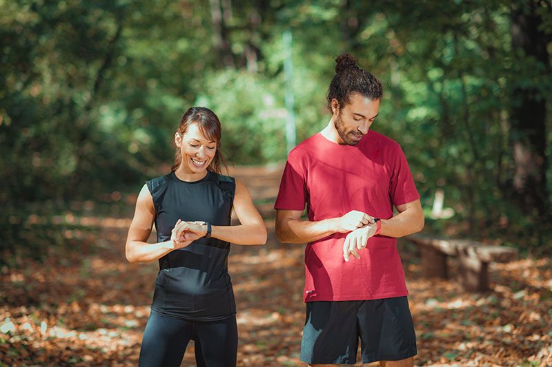 Young couple looking at smart watches before workout